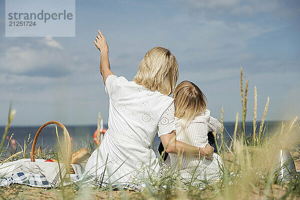 Mother and daughter sitting on picnic and looking on skyline