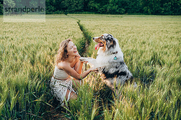 joyful scene of a young woman playing with her australian shepherd dog