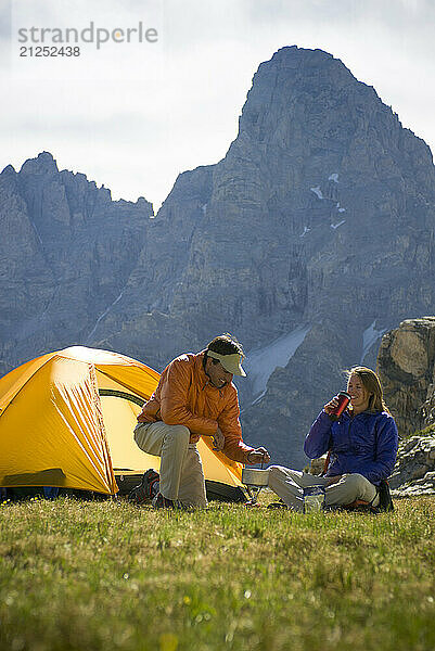 A young couple cooks dinner while camping in the high alpine of the Teton Range  Wyoming.