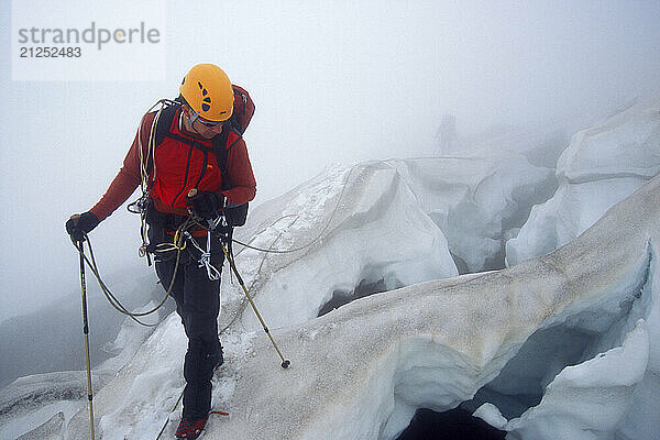 Climber Kendall Ermshar crossing dangerous crevasse fields in the fog on the Winthop Glacier while approaching the popular Liberty Ridge on the North side of Washingon's Mt. Rainier. Mount Rainier National Park is in the Cascades Mounain Range near Seattle  and is very popular for skiing and mountaineering.