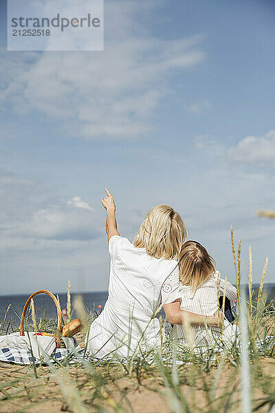 Mother and daughter sitting on picnic and looking on skyline