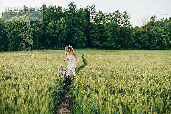 woman enjoying with her australian shepherd in a green rye field