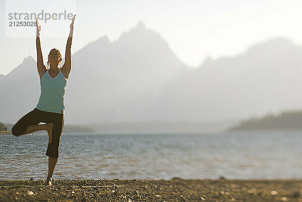 A young woman practices yoga on the shore of Jackson Lake in Grand Teton National Park  Jackson Hole  Wyoming (selective focus).