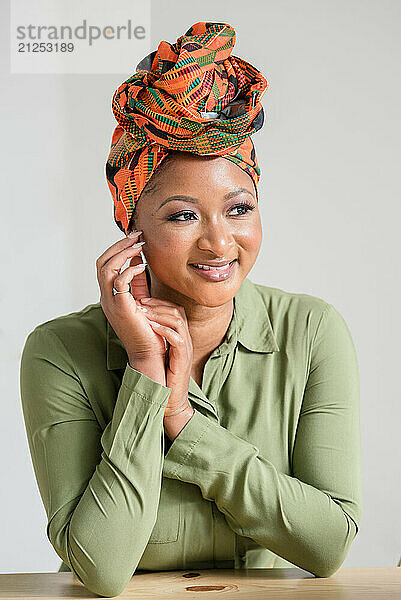 Woman smiling and leaning on a table with an African headwrap