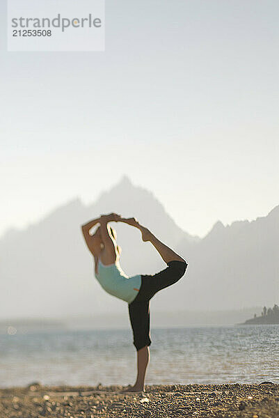 A young woman practices yoga on the shore of Jackson Lake in Grand Teton National Park  Jackson Hole  Wyoming (selective focus).