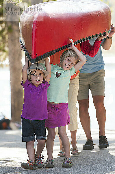 Two young girls help the family carry a canoe in Grand Teton National Park  Jackson Hole  Wyoming.