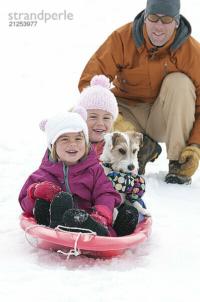 Two elementary age girls go sledding with their dog in Jackson Hole  Wyoming.