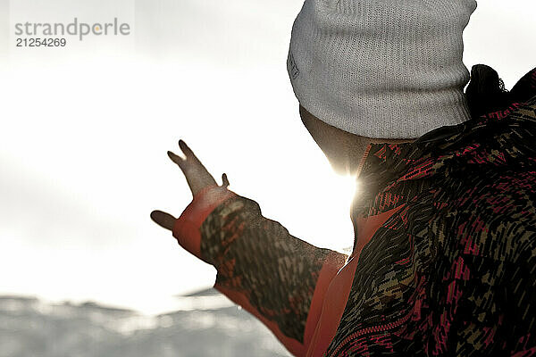 Snowboarder shielding face from glariing sun