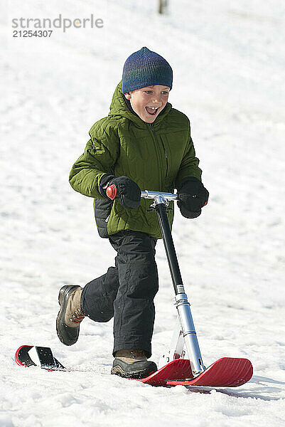 A boy smiles while riding a snow scooter in Jackson  Wyoming.