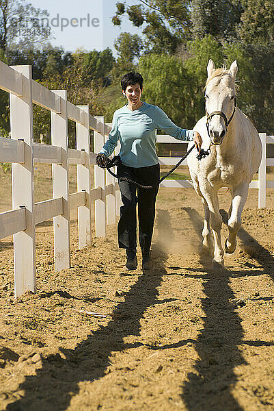 A young woman smiles as she runs with her horse in southern California.