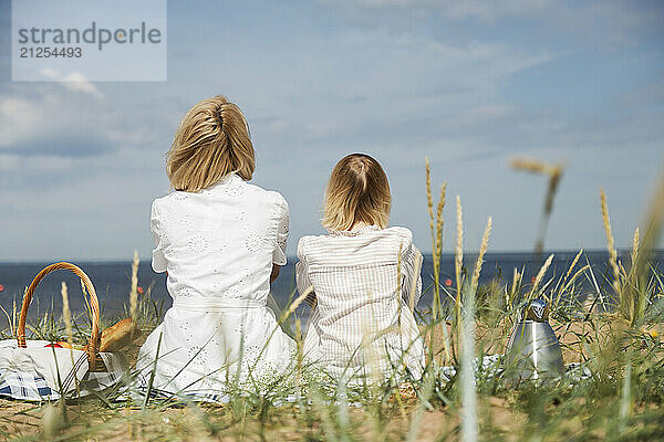 Mother and daughter sitting on picnic and looking on skyline