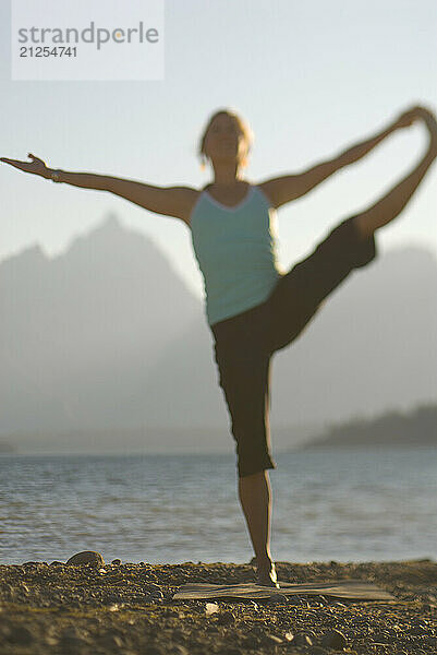 A young woman practices yoga on the shore of Jackson Lake in Grand Teton National Park  Jackson Hole  Wyoming (selective focus).