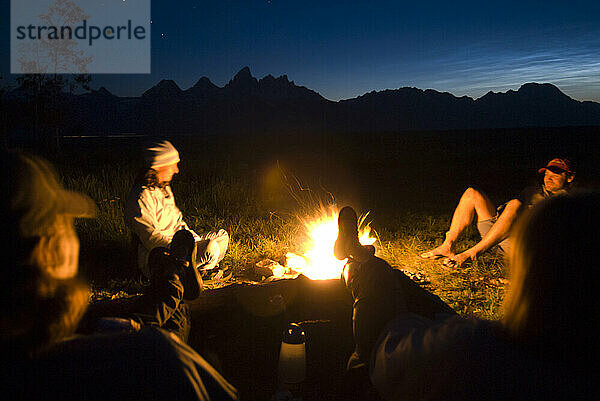 A group of friends relax around a campfire at dusk in Jackson Hole  Wyoming.