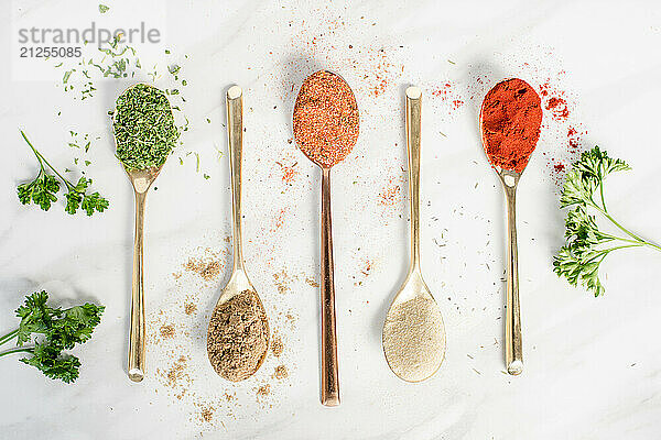 Five different spices in spoons on a table