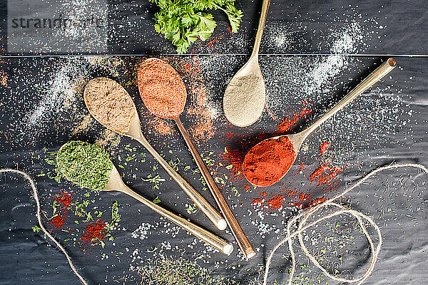 Spices sprinkled around on table with spoons