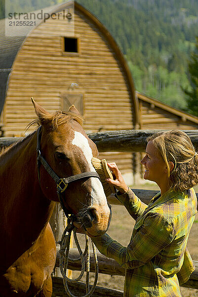 A young woman grooms her horse at a ranch in Wilson  Wyoming.