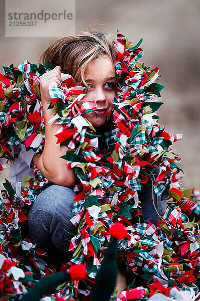 Boy sitting playing hide and seek with Christmas decorations