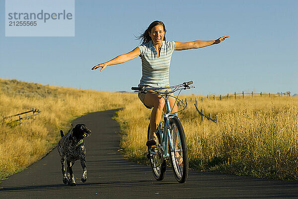 A young woman rides along a bike path with her dog in Jackson Hole  Wyoming.