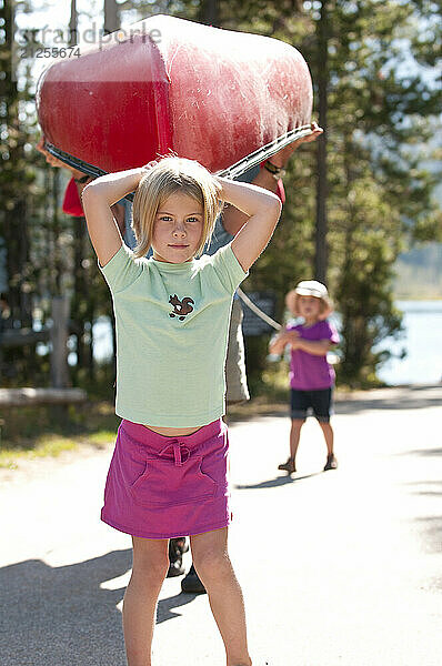 A young girl helps the family carry a canoe in Grand Teton National Park  Jackson Hole  Wyoming.