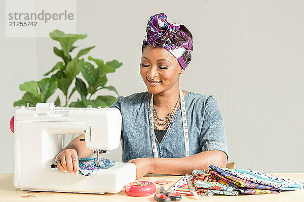 Woman using a sowing machine to make headwraps