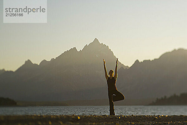 A young woman practices yoga on the shore of Jackson Lake in Grand Teton National Park  Jackson Hole  Wyoming (selective focus).