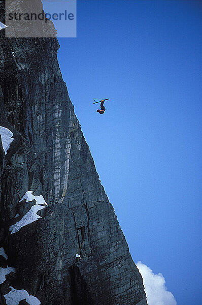 Ski-BASE jumper doing a front flip at Lover's Leap  near Lake Tahoe California. Ski-BASEing is a hybrid of extreme skiing and BASE jumping in which one skis of a steep cliff with a parachute.