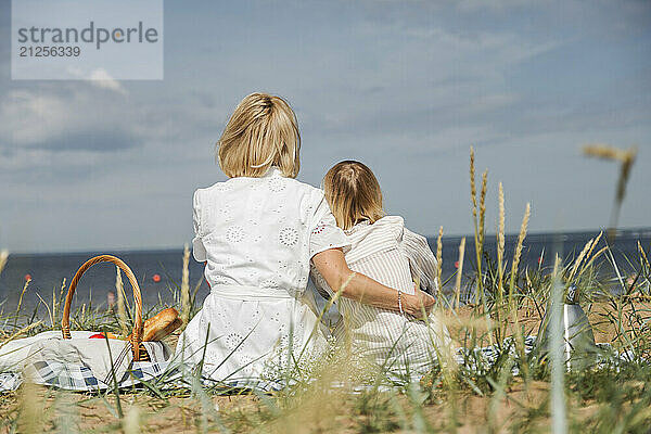 Mother and daughter sitting on picnic and looking on skyline