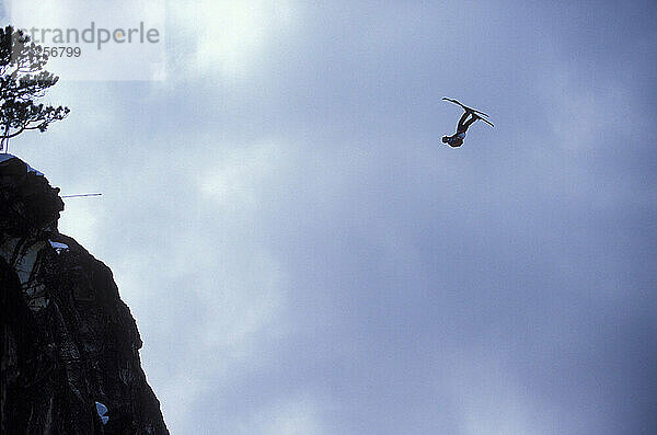 Miles Daisher pulling a front flip while ski-BASE jumping at Lover's Leap  near Lake Tahoe. Ski-BASEing is a hybrid of extreme skiing and BASE jumping in which one skis of a steep cliff with a parachute.