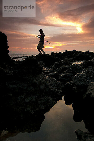 A young woman hula hoops at sunset near Kihea in Maui  Hawaii.