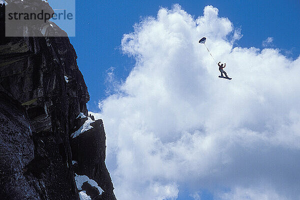 Mark Ridley pulling a back flip while Snowboard-BASE jumping at Lover's Leap  near Lake Tahoe. Board-BASEing is a hybrid of extreme snowboarding and BASE jumping in which one rides off a steep cliff with a parachute.