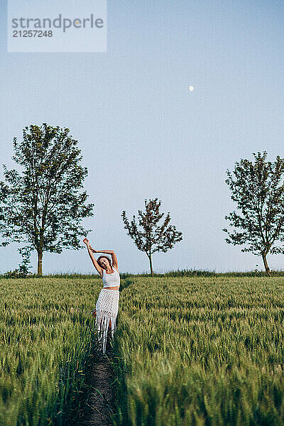 Young woman dreams in a green field on a summer evening