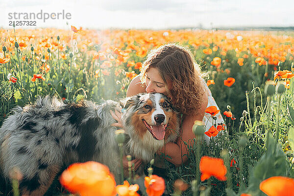 Beautiful young woman and australian shepherd dog in poppy field