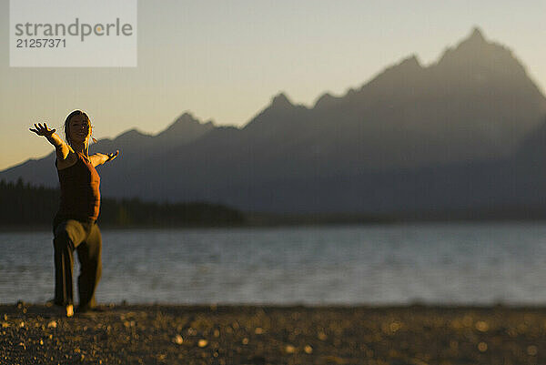 A young woman practices yoga on the shore of Jackson Lake in Grand Teton National Park  Jackson Hole  Wyoming (selective focus).