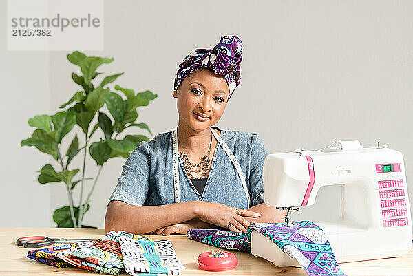 Nigerian woman posing in front of sowing machine and fabric