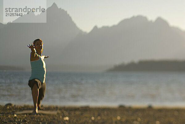 A young woman practices yoga on the shore of Jackson Lake in Grand Teton National Park  Jackson Hole  Wyoming (selective focus).