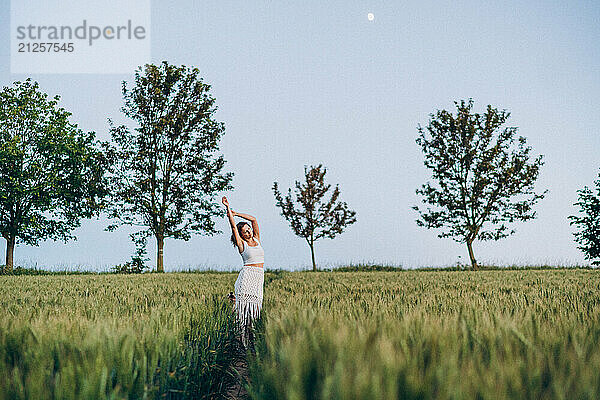 Young woman dreams in a green field on a summer evening