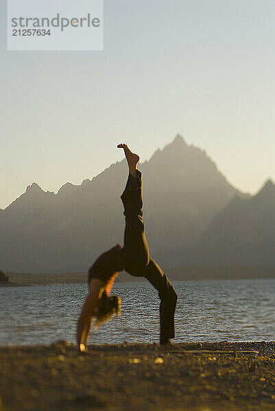 A young woman practices yoga on the shore of Jackson Lake in Grand Teton National Park  Jackson Hole  Wyoming (selective focus).