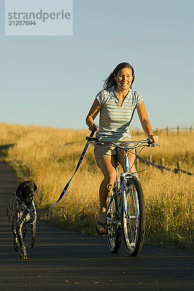 A young woman rides along a bike path with her dog in Jackson Hole  Wyoming.