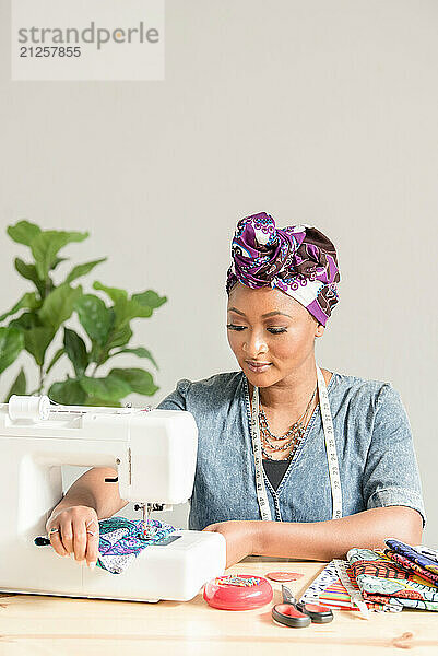 Woman pushing fabric through sowing machine