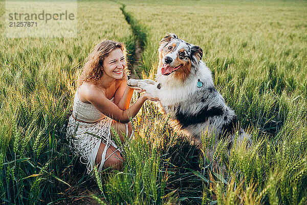 woman playing with her dog in a vibrant green rye field