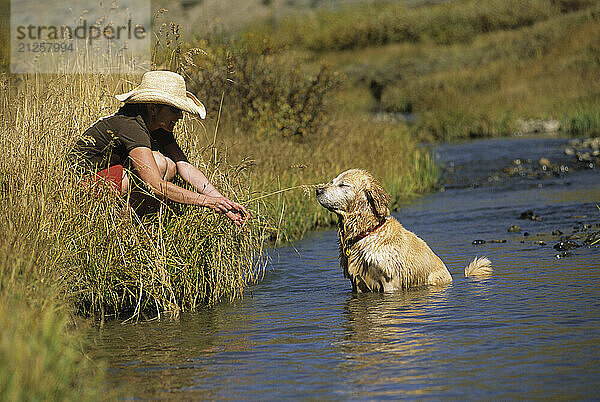 A young woman plays with her dog at a creek near Crested Butte  Colorado.