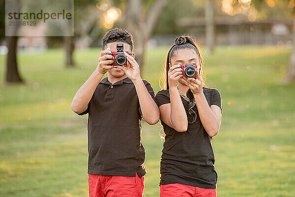 Brother and sister using their cameras to take a pictures