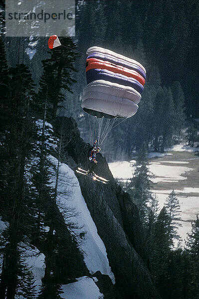 Miles Daisher landing his parachute while ski-BASE jumping at Lover's Leap  near Lake Tahoe. Ski-BASEing is a hybrid of extreme skiing and BASE jumping in which one skis of a steep cliff with a parachute.