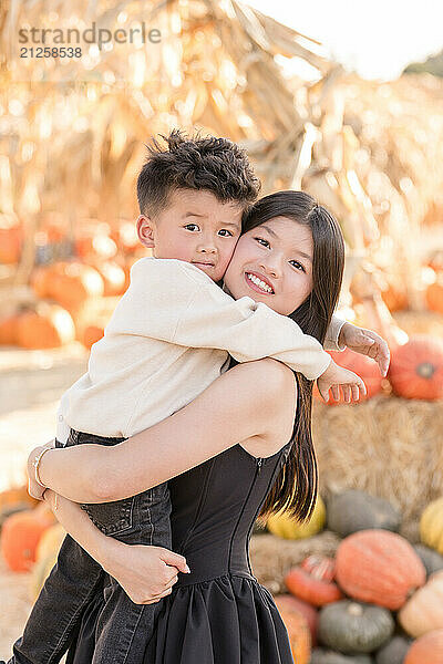 Sister holding brother in a pumpkin patch