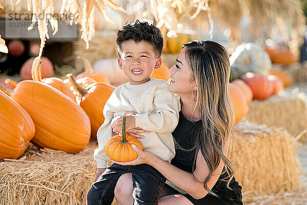 Little boy laughing with mother in a pumpkin patch