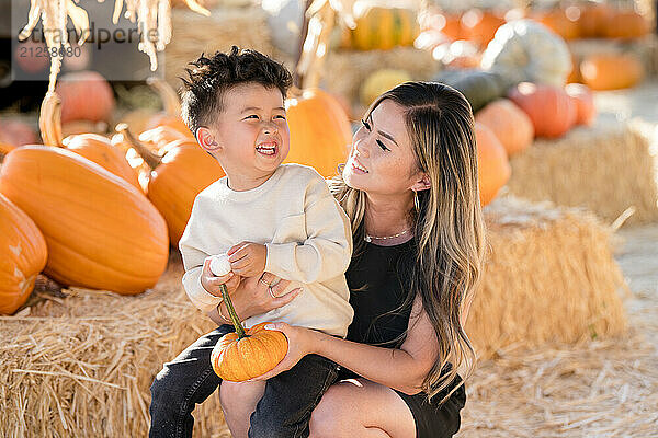 Mother and son laughing together in a pumpkin patch