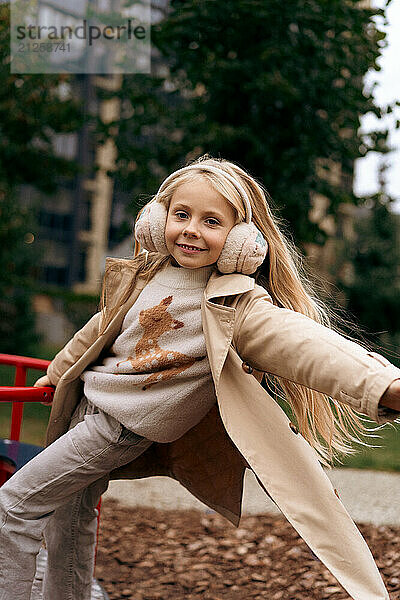 Cheerful girl playing on swing at park during autumn