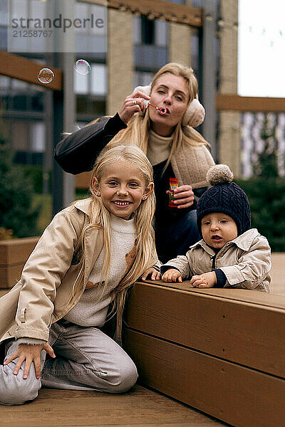 Mom spends time with two children in the park  blows soap bubbles