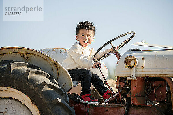 Little boy playing on an old tractor