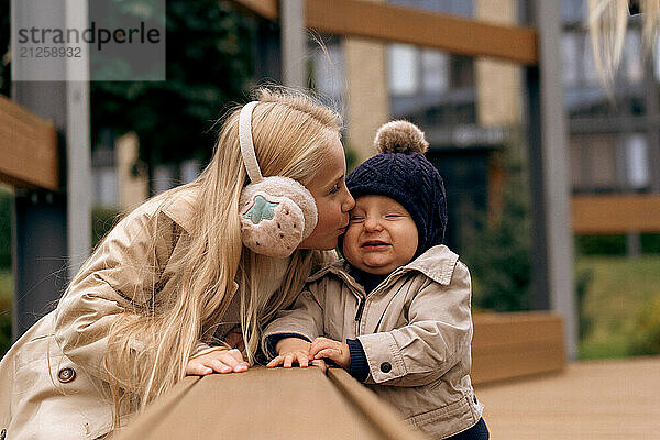 Sister kisses her younger little brother in the park